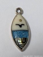 Front view of the vintage bird pendant showing details of the bird silhouette, textured blue midsection, and iridescent lower section with an alpaca metal frame.