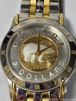 Close-up of watch dial showing Canadian $2 coin with gold plated polar bear and surrounding text.
