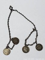 Full view of silver twisted link chain necklace with three attached England 3 pence silver coins.