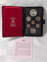 Opened coin case showing seven Canadian coins including two large silver double dollar coins and an informational card.