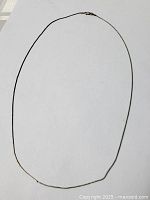 Full view of the thin sterling silver necklace against a white background, showing the entire chain and clasp.