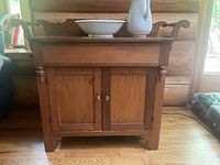 Front view of antique wooden wash stand with water jug and basin on top
