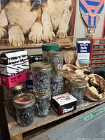 Photo showing jars, boxes, and packages of assorted nails and screws on a shelf.