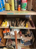 Photo showing shelves with assorted hand tools including chisels, utility knife, scissors, wire stripper, flashlight, and electrical wiring accessories.