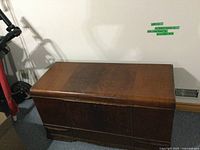 Closed rectangular cedar chest showing wood grain finish and rivet detailing on faces.