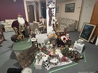 Wide shot of entire lot including large Santa figure, snowman decoration, and various assorted ornaments and decorations arranged on tables and floor.