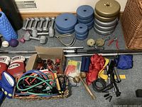 Overview of dumbbells, weight plates, barbells, small bar, hand grips and basket of ropes and bands