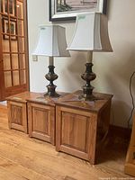 Three pine nesting tables with brass lamps on top, showing front and side views.