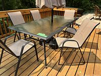 Group view of rectangular patio table with six sling chairs on wooden deck