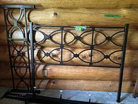 Full view of disassembled metal bed frame components including headboard and footboard against a wood wall.