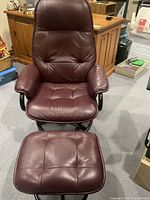 Front view of burgundy leather swivel chair and ottoman on carpeted floor
