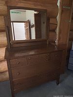 Front view of the vintage wooden dresser with mirror, showing five drawers and a rectangular mirror attached to the back.