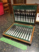 Photo showing the full set of 12 fish knives and forks in a wooden box with green felt lining.