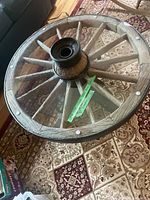 Top-down view of round coffee table with wagon wheel base and glass surface, showing wood grain and metal ring hub.