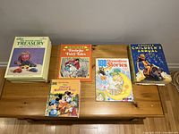 Collection of 5 assorted children's hardcover books including Sesame Street Treasury, Favorite Fairy Tales, 180 Dreamtime Stories, Simpson's Children's Annual, and a Disney-themed book featuring Mickey Mouse and friends.