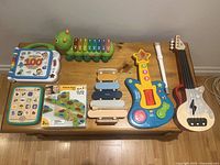 Top view of various musical toys including xylophone, guitar, and tablet