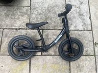 Side view of black Jollito balance bike on tiled floor showing frame, wheels, and seat.