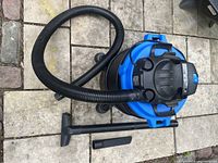 Mastervac wet/dry vacuum cleaner with flexible hose and floor attachment on paved surface.