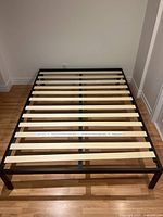 Queen size metal platform bed with black metal frame and natural wood slats viewed from above showing slatted base and sturdy construction.
