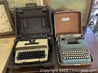 Both vintage electric typewriters in open cases showing wear and electrical cords.