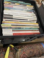 Photo showing top view of assorted architecture and interior design magazines stacked upright in a black milk crate. Titles visible include Interior Design, Architectural Record, Evo, and Houses magazines, among others.
