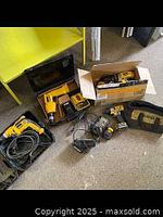 View of assorted DeWalt drills and drivers, batteries, chargers and cases on the floor including a soft carrying bag
