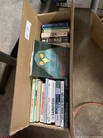 Overhead image showing the box of assorted books with visible titles including 'Improve Your Brain Power,' 'The Complete Runner,' and 'Samoyeds.'