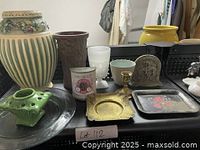 Image showing the assortment of decorative items including vases, trays, flower frog, candlestick holder, and ceramic figurine arranged on a black plastic crate.