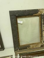 Close-up of a single embossed dark wood picture frame with no glass and chipped paint