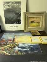 Photo of assorted framed and unframed art including Ansel Adams black and white print and paintings