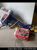 White and blue Honda 4 Stroke CDI 100 outboard motor connected to the lower unit and propeller, resting on the floor with yellow rope around it.