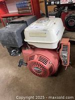 Full profile side view of Honda GX390 engine showing white fuel tank, red body, recoil starter and ignition control box on the side.