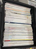 Photo of magazines stacked in a black plastic bin showing visible spines with titles Eco-Structure, Metropolitan Home, Architectural Digest
