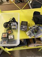 Entire lot laid out showing Gameboy Color handheld, five game cartridges, power adapter, Handypak Color light attachment, and carrying case