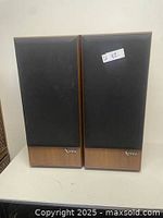 Front view of two Infinity SM 112 floor speakers with fabric grilles and wood veneer cabinets