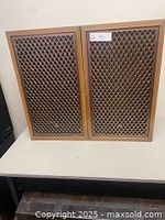 Frontal view of both speakers showing wood veneer cabinets and grilles