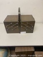 Closed expanding wooden sewing box with a dark finish and a central handle.