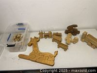 Wooden giraffe puzzle assembled and laid flat beside small wooden train pieces and an airplane figurine.