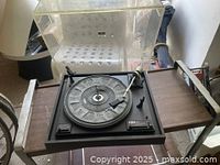Vintage BIC 920 turntable record player on wooden table with acrylic dust cover raised, showing tonearm and platter