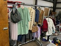 Photo of rack with vintage clothing items and handbag, showing variety of coats, sweaters, blouse, and accessories