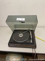 Vintage Garrard 42M turntable with dust cover open, showing platter and tonearm on white table surface.