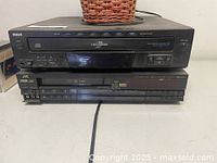 Photo of RCA 5 Disc Changer CD Player stacked on top of JVC VCR showing front panels and buttons.