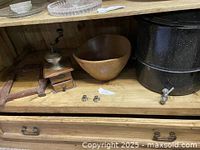 Photo of shelf with vintage manual coffee grinder, teak salad bowl, wooden frame, and black speckled stockpot with spigot