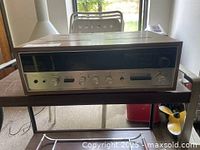 Front and side view of the vintage Sansui 2000X stereo receiver on a table, showing wood veneer and metal faceplate controls.