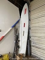 Photo showing the vintage Sprinter windsurfing board with red and black handle inserts and venting hole, displayed vertically.