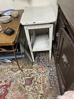 Top-down angled view of the vintage white metal medical stand showing surface wear and surrounding items for scale.