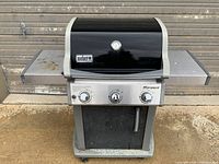 Front view of Weber Spirit gas grill showing control knobs, lid with temperature gauge, and side tables