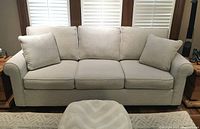Front view of the three-seat sofa with two square throw pillows placed at each end
