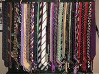 Photo of approximately 31 vintage neckties hanging showing a variety of designs and colors including stripes, geometric, and floral patterns.