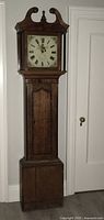 Full view of the antique wooden grandfather clock showing entire height and design details.